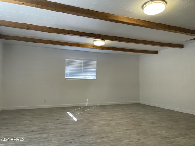 unfurnished room with beam ceiling and light wood-type flooring