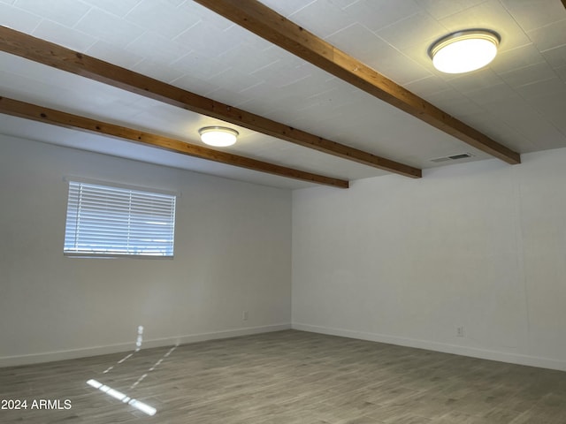 spare room featuring beam ceiling and light wood-type flooring