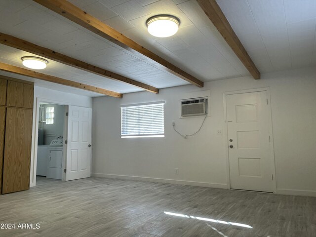 basement with washer / clothes dryer, a wall mounted AC, and light hardwood / wood-style floors