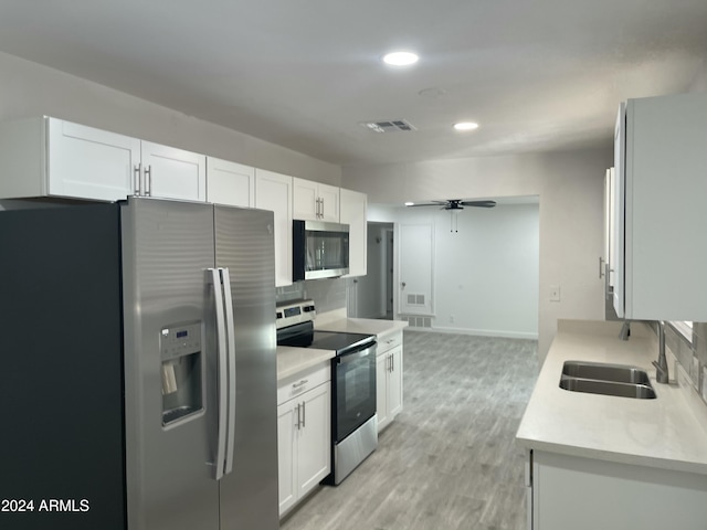 kitchen with decorative backsplash, ceiling fan, light wood-type flooring, white cabinetry, and stainless steel appliances