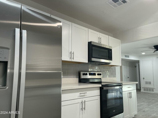 kitchen with ceiling fan, stainless steel appliances, tasteful backsplash, white cabinets, and light wood-type flooring