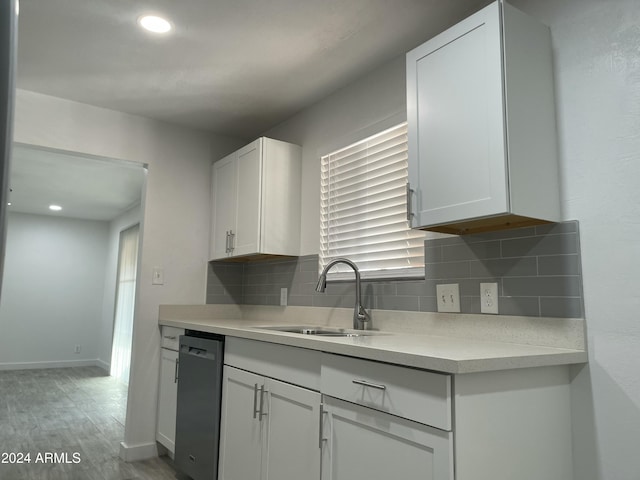 kitchen with white cabinetry, dishwasher, sink, tasteful backsplash, and light hardwood / wood-style flooring