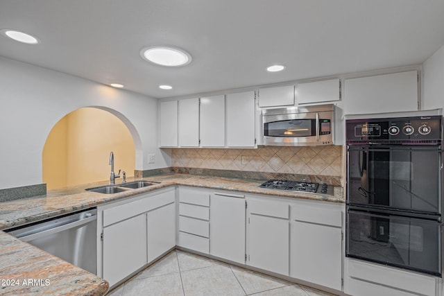 kitchen with decorative backsplash, stainless steel appliances, sink, white cabinetry, and light tile patterned flooring