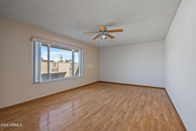 spare room featuring ceiling fan, light wood-type flooring, and a textured ceiling