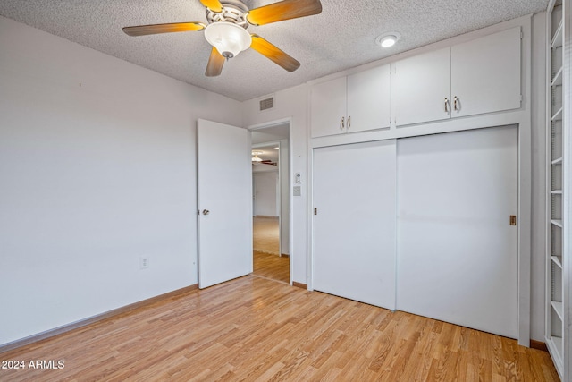 unfurnished bedroom featuring ceiling fan, a closet, a textured ceiling, and light wood-type flooring