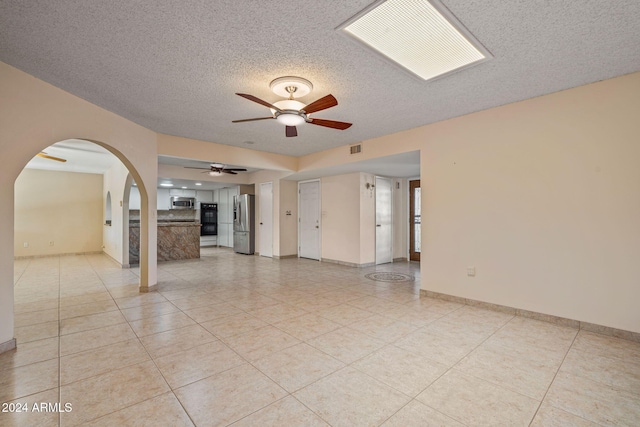 unfurnished room featuring a textured ceiling, ceiling fan, and light tile patterned flooring