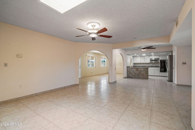 unfurnished living room with light tile patterned floors, a textured ceiling, and ceiling fan