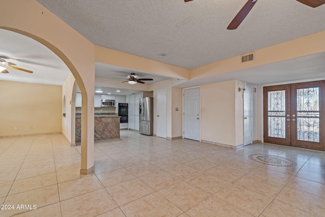 unfurnished room featuring french doors, a textured ceiling, light tile patterned floors, and ceiling fan