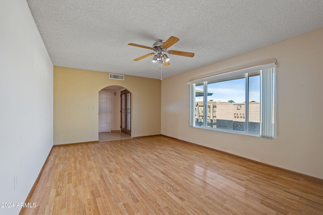 unfurnished room featuring a textured ceiling, light wood-type flooring, and ceiling fan