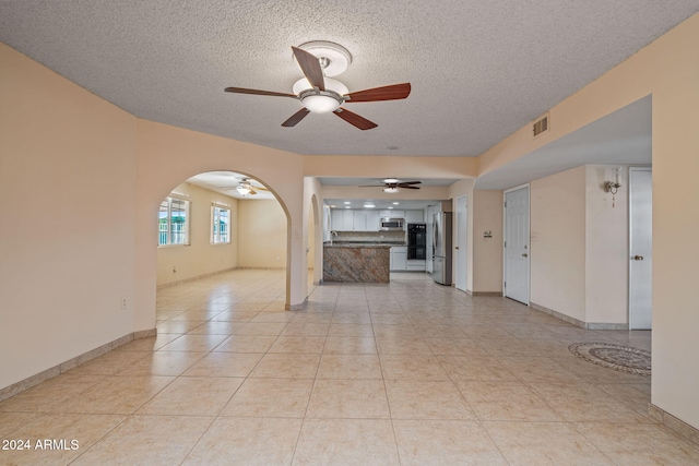 unfurnished living room featuring light tile patterned floors, a textured ceiling, and ceiling fan