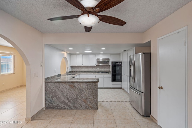 kitchen featuring kitchen peninsula, appliances with stainless steel finishes, ceiling fan, white cabinets, and light tile patterned flooring