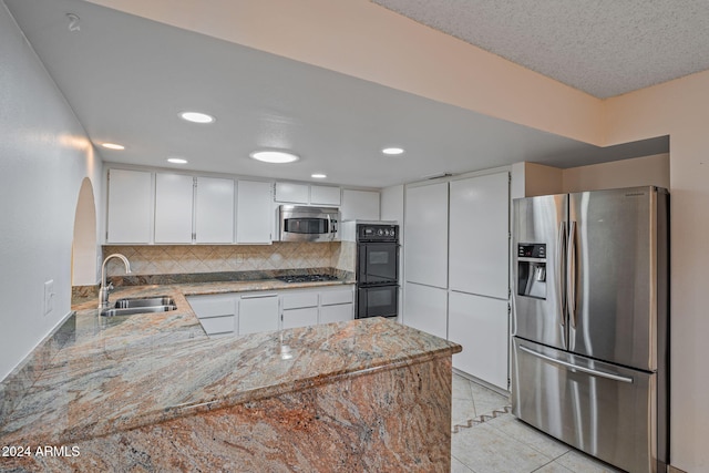 kitchen featuring white cabinets, sink, tasteful backsplash, kitchen peninsula, and stainless steel appliances