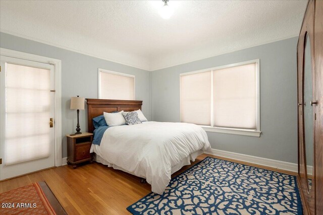 bedroom with ornamental molding, a textured ceiling, and light hardwood / wood-style floors