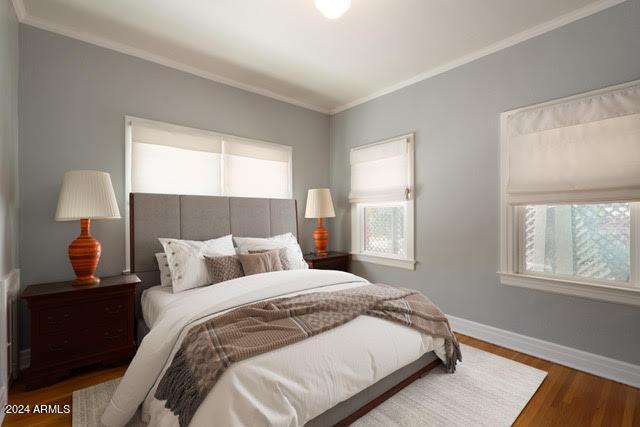 bedroom with crown molding and dark wood-type flooring