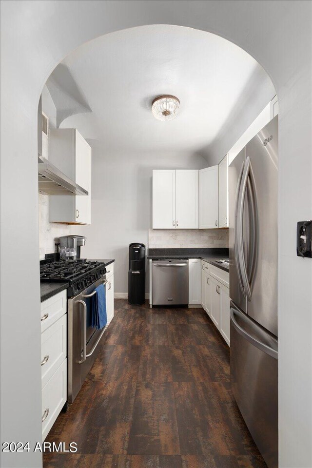 kitchen featuring wall chimney range hood, stainless steel appliances, dark hardwood / wood-style floors, and white cabinetry