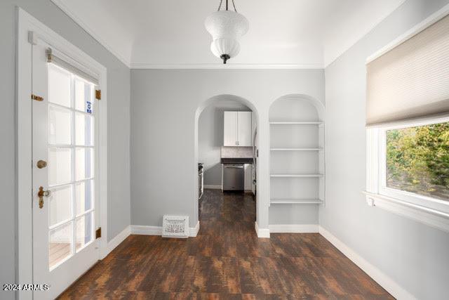 empty room with a wealth of natural light, dark hardwood / wood-style floors, and crown molding