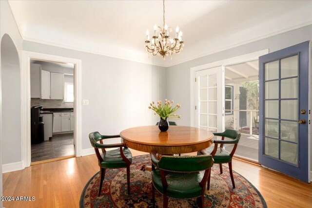 dining area with crown molding, light hardwood / wood-style flooring, and a notable chandelier