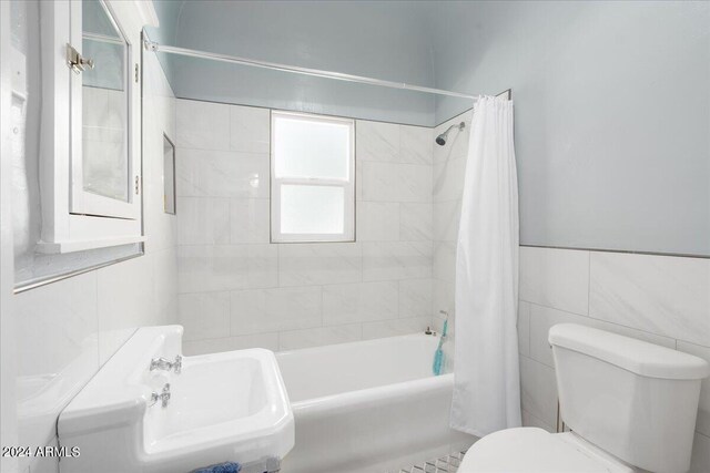 bathroom with tile walls, toilet, and shower / tub combo