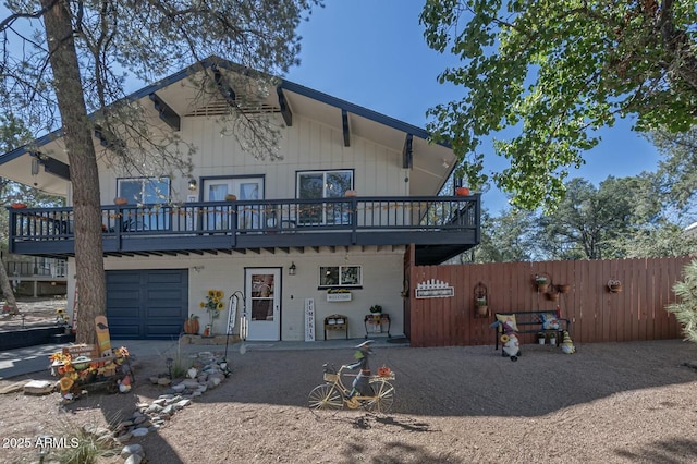 view of front of house featuring fence, dirt driveway, a deck, and a garage