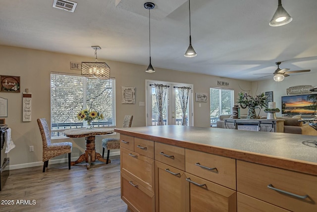 kitchen featuring wood finished floors, visible vents, baseboards, hanging light fixtures, and ceiling fan