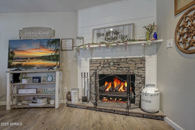 details with a stone fireplace, wood finished floors, and baseboards