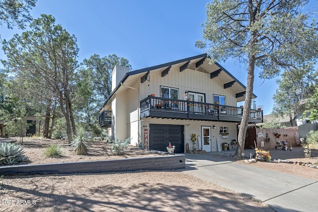 view of front of house featuring a garage, a wooden deck, a chimney, and concrete driveway