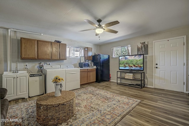 clothes washing area featuring a ceiling fan, wood finished floors, plenty of natural light, washing machine and dryer, and laundry area