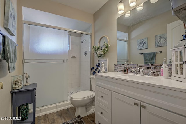 bathroom featuring toilet, tasteful backsplash, wood finished floors, and a stall shower