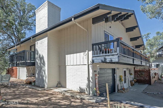 view of side of home featuring brick siding, a balcony, and a garage