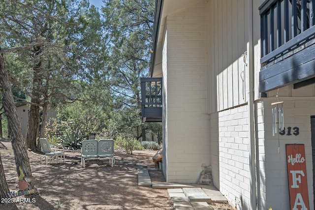 view of home's exterior with brick siding, a patio area, and a balcony
