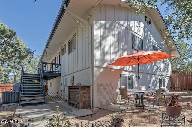 rear view of house featuring a patio area, central AC, stairs, and fence