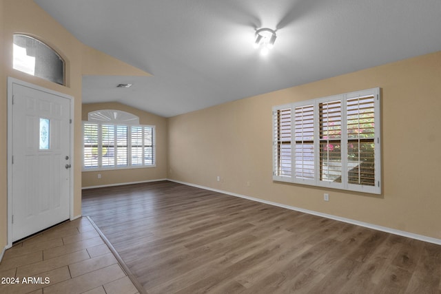 foyer entrance with wood-type flooring and vaulted ceiling