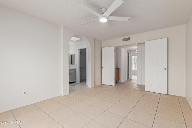 702 W Sequoia Dr, Phoenix, AZ 85027 - unfurnished bedroom with arched walkways, a textured ceiling, light tile patterned floors, and ceiling fan