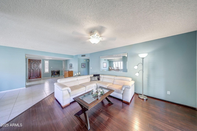 living area featuring baseboards, plenty of natural light, a textured ceiling, and ceiling fan