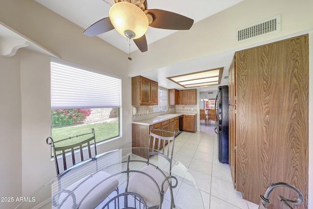 kitchen featuring brown cabinets, a sink, light countertops, freestanding refrigerator, and visible vents