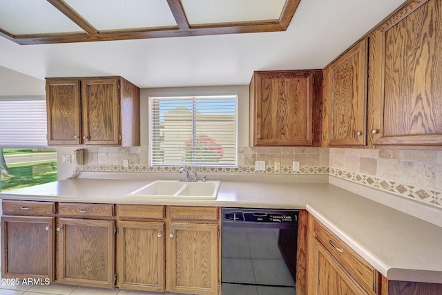 kitchen featuring a sink, decorative backsplash, black dishwasher, and light countertops