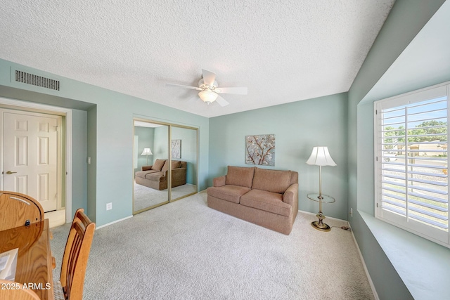 carpeted living area featuring visible vents, a ceiling fan, a textured ceiling, and baseboards