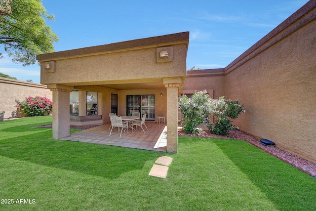 back of property with a patio, a lawn, and stucco siding
