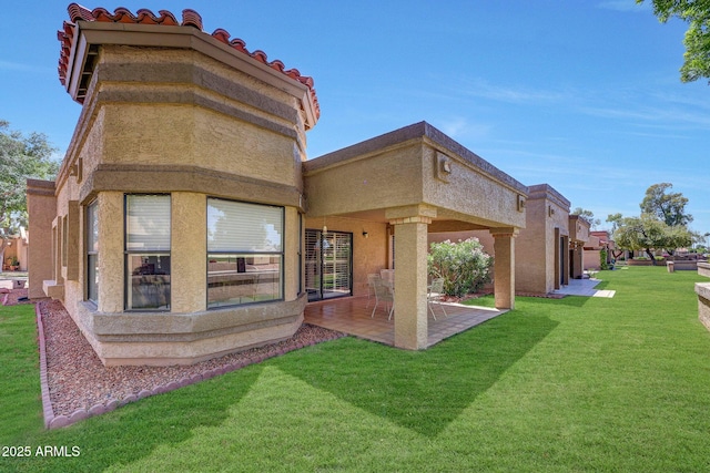 rear view of property with a patio, a lawn, and stucco siding