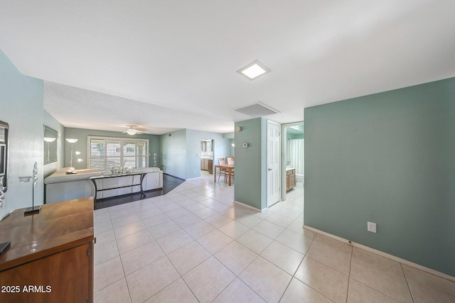 interior space with baseboards, a ceiling fan, light tile patterned floors, and visible vents