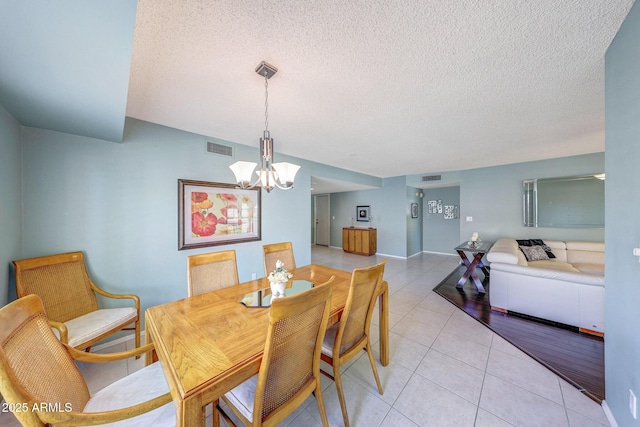 dining area featuring a textured ceiling, a chandelier, light tile patterned floors, and visible vents