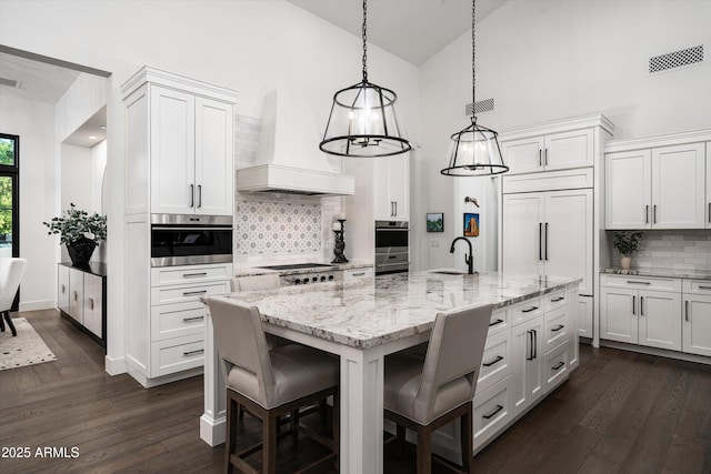 kitchen featuring backsplash, a sink, premium range hood, high vaulted ceiling, and white cabinetry