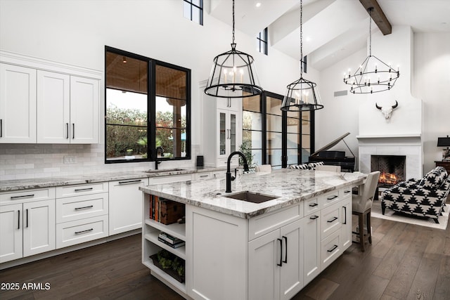 kitchen featuring white cabinets, beamed ceiling, a sink, and high vaulted ceiling