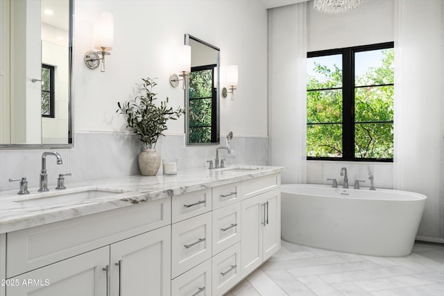 full bathroom featuring a sink, tile walls, double vanity, and a healthy amount of sunlight