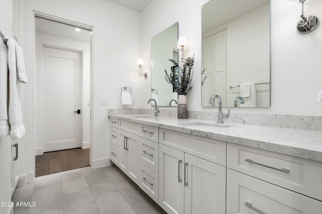 bathroom featuring baseboards, double vanity, tile patterned floors, and a sink