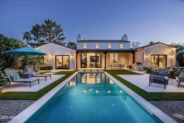 back of property with a patio, an outdoor pool, stucco siding, and a chimney