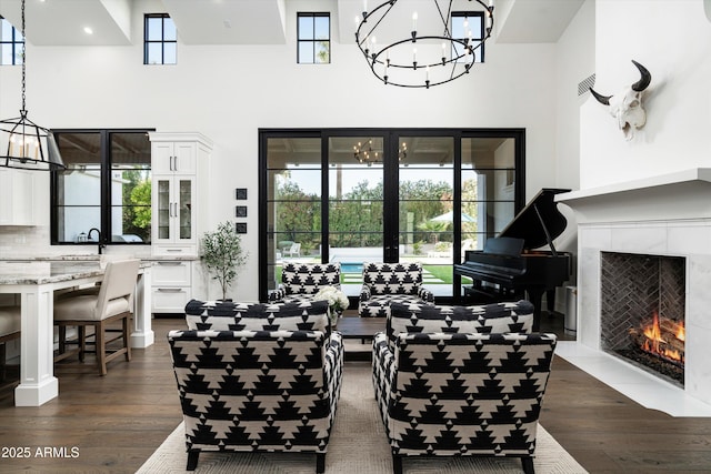 living area featuring an inviting chandelier, a high ceiling, dark wood-style floors, and a premium fireplace