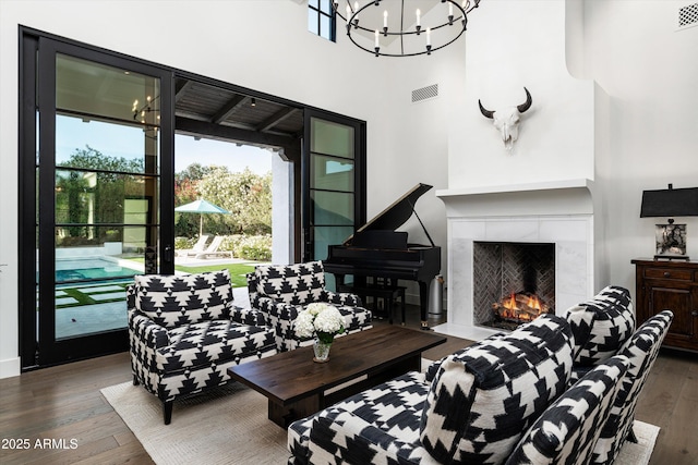 living room with visible vents, wood finished floors, a chandelier, and a fireplace