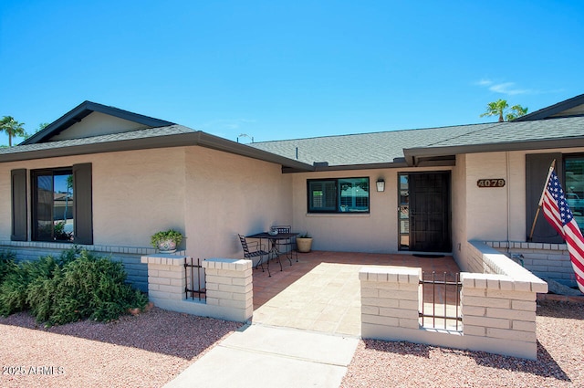 4079 E Shangri La Rd, Phoenix, AZ 85028 - view of exterior entry featuring stucco siding, a shingled roof, and a patio area