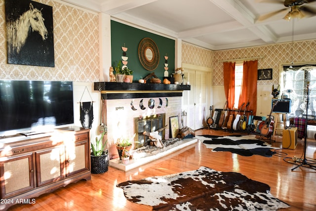 living room featuring beamed ceiling, hardwood / wood-style floors, a brick fireplace, and ceiling fan